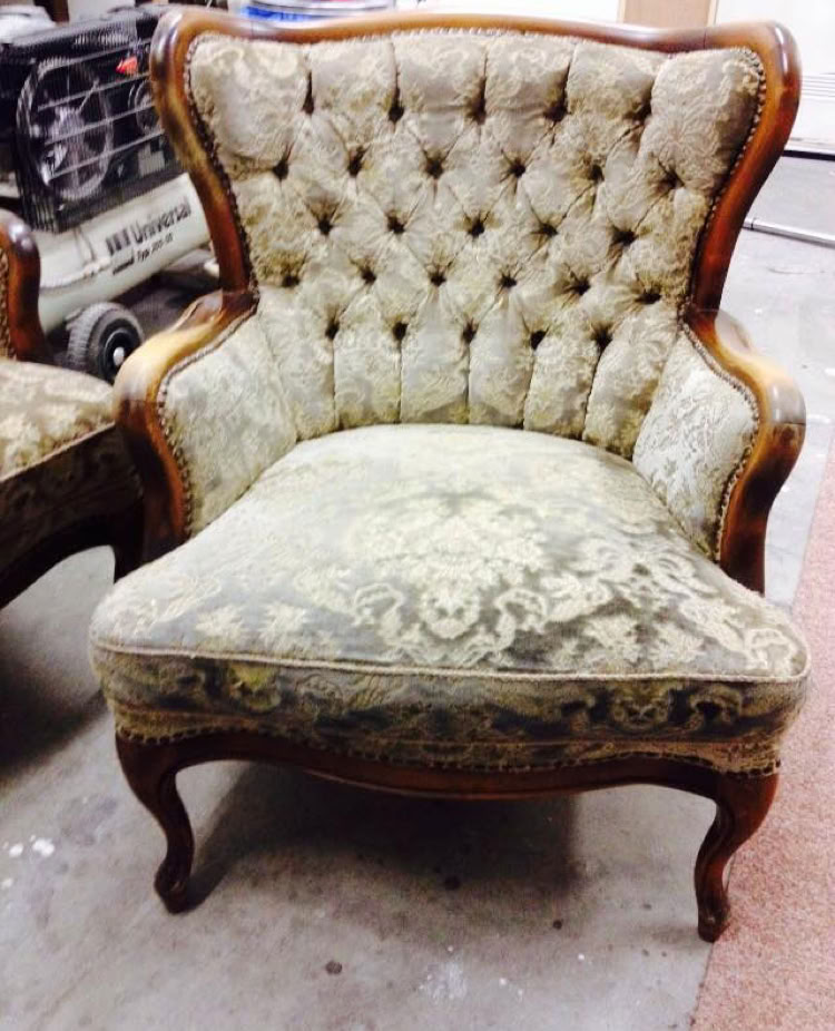 Ein gepolsterter Sessel mit Holzrahmen und Knopfheftung auf der Rückenlehne.